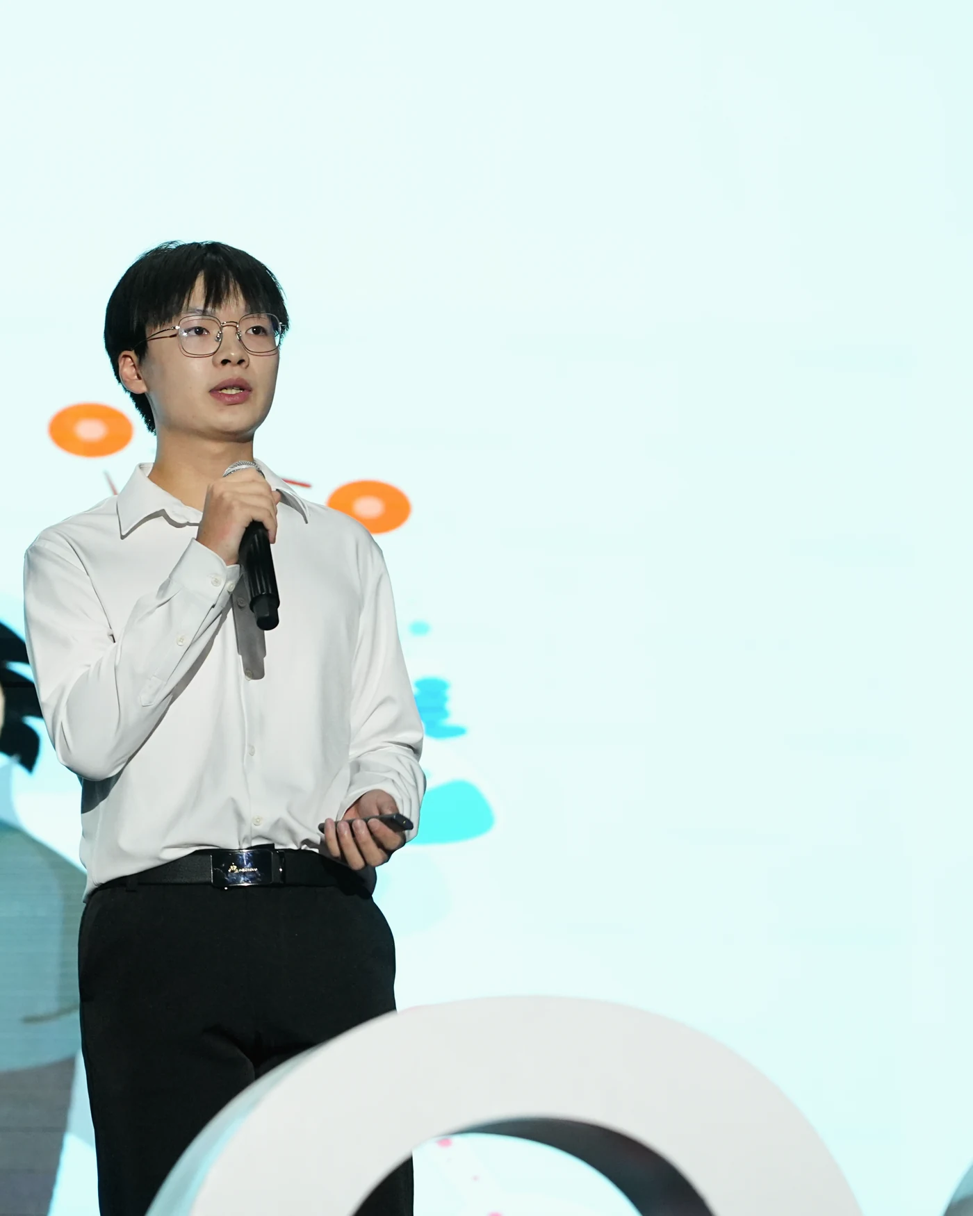 Jacky Huang speaking into a microphone on the TEDx stage.