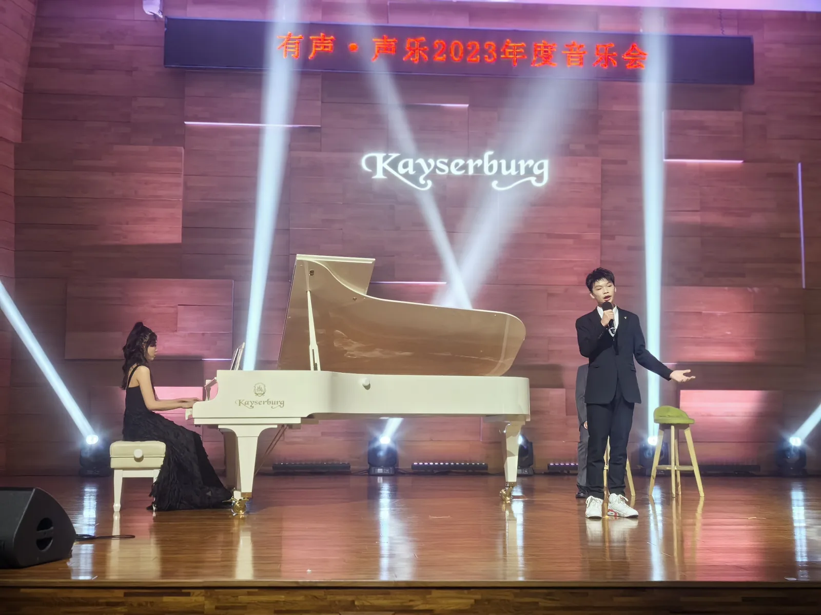 Jacky performing on stage with a piano and drum kit.