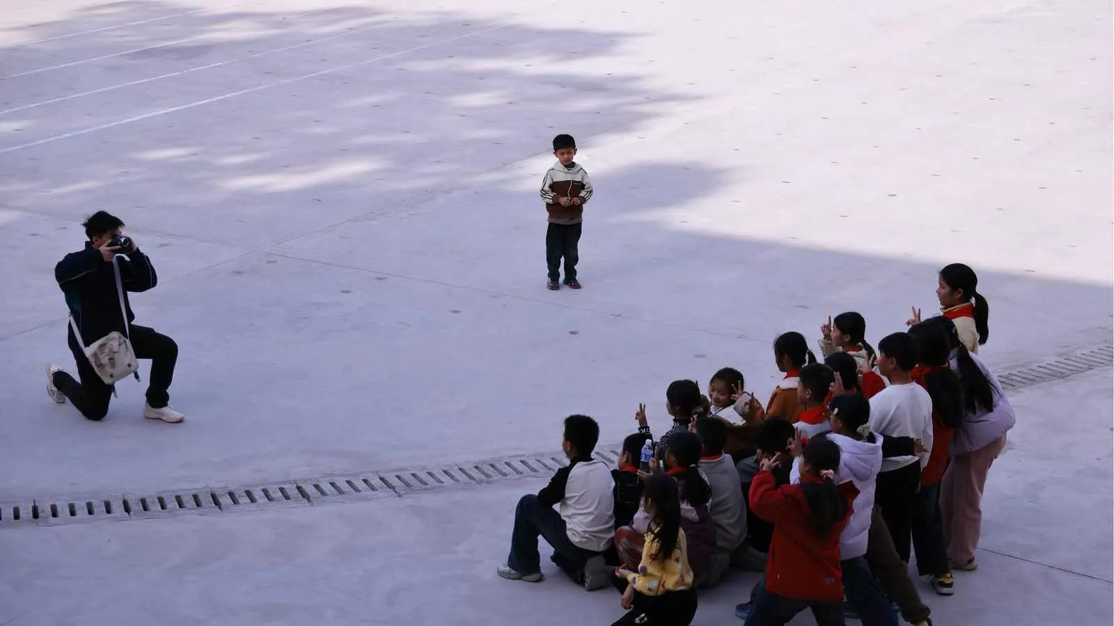 A wide view of students gathered in a circle at a rural primary school.